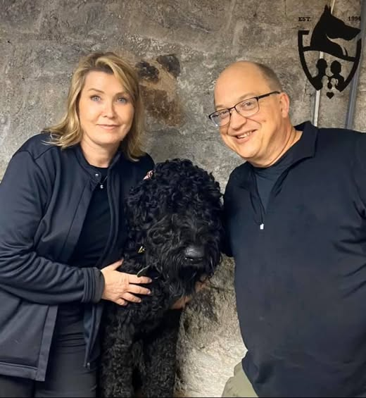two people with a black dog.