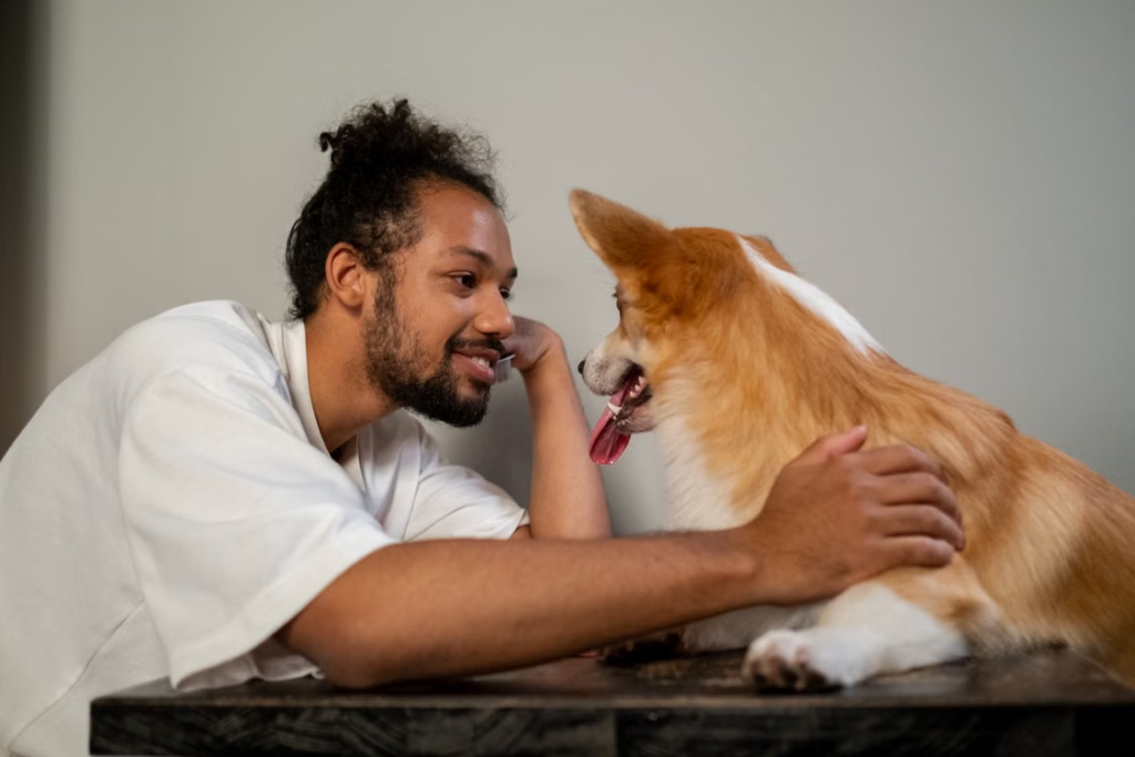 a dog owner in a white T-shirt playing with his dog.